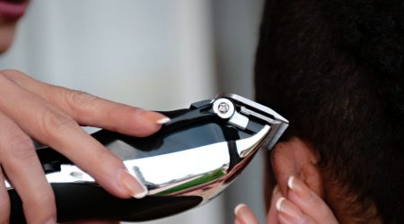 A barber uses scissors to texturize a male client's thick hair in a modern salon.