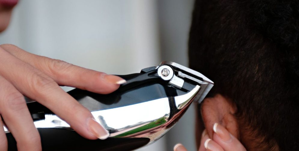 A barber uses scissors to texturize a male client's thick hair in a modern salon.