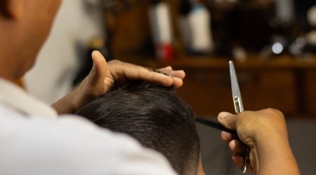 Барбер підстригає хвилясте волосся чоловіка в салоні.