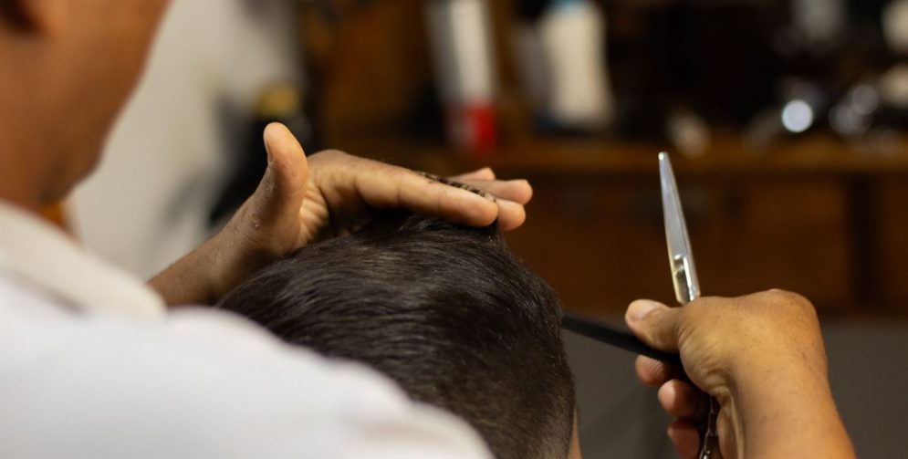 Барбер підстригає хвилясте волосся чоловіка в салоні.